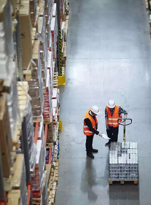 experts du destokage qui montrent des marchandises emballées sur des palettes portées par un chariot élévateur dans un entrepôt de stockage