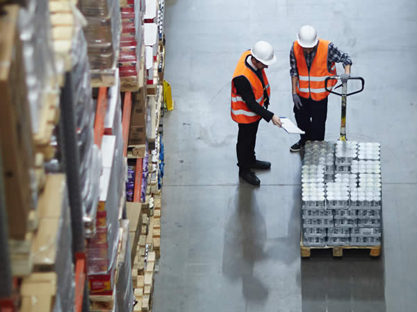 experts du destokage qui montrent des marchandises emballées sur des palettes portées par un chariot élévateur dans un entrepôt de stockage