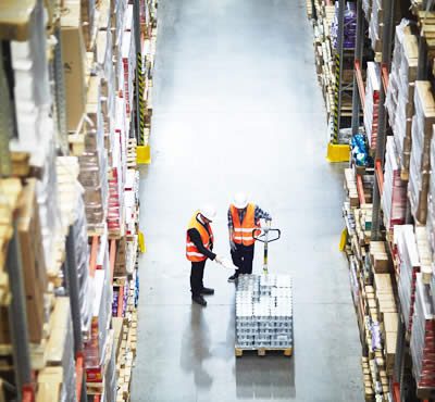 experts du destokage qui montrent des marchandises emballées sur des palettes portées par un chariot élévateur dans un entrepôt de stockage