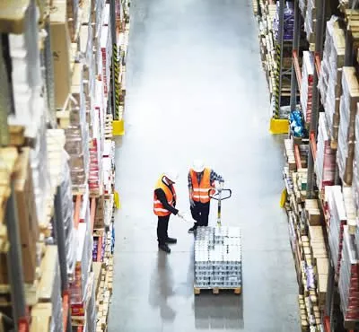 experts du destokage qui montrent des marchandises emballées sur des palettes portées par un chariot élévateur dans un entrepôt de stockage