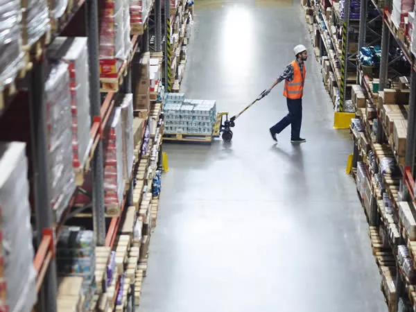 soldeur destockeur qui tire un chariot élévateur rempli de cartons de produits pour la maison et la cuisine