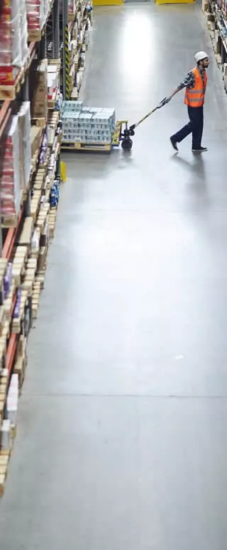 soldeur destockeur qui tire un chariot élévateur rempli de cartons de produits pour la maison et la cuisine