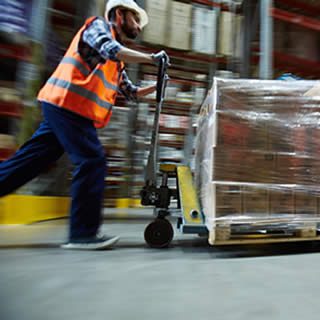 homme qui porte un gilet fluorescent orange et un casque de protection pour assurer sa sécurité dans l'entrepôt de destockage